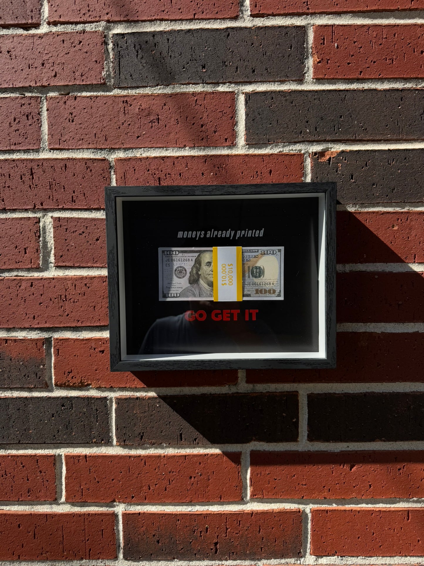 Black handmade shadow box with prop bills and the red command Go Get It