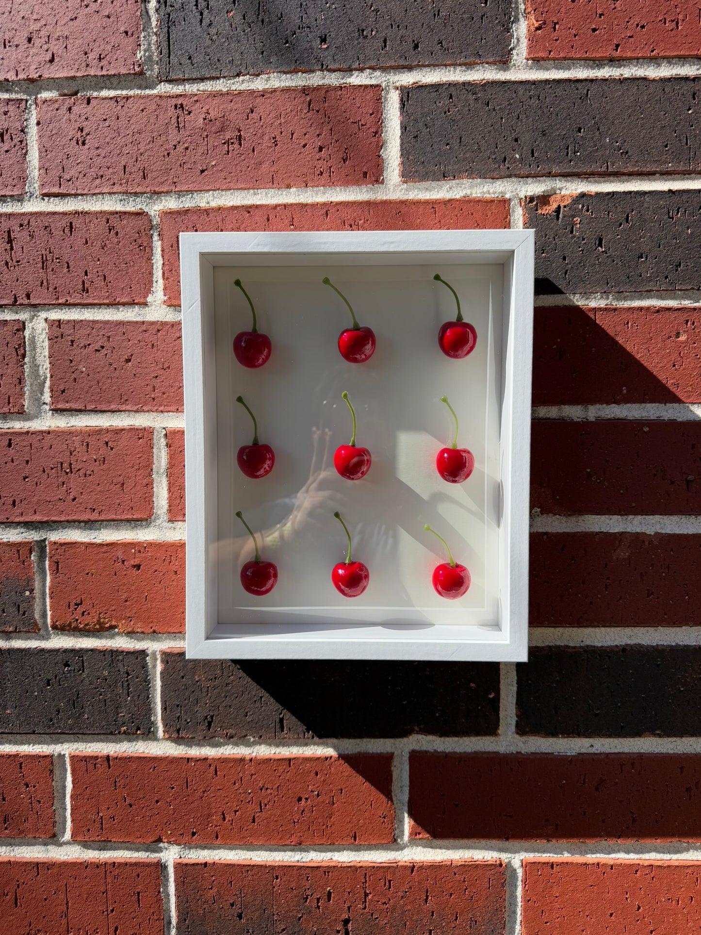 Handmade white shadow box with nine glossy red cherries