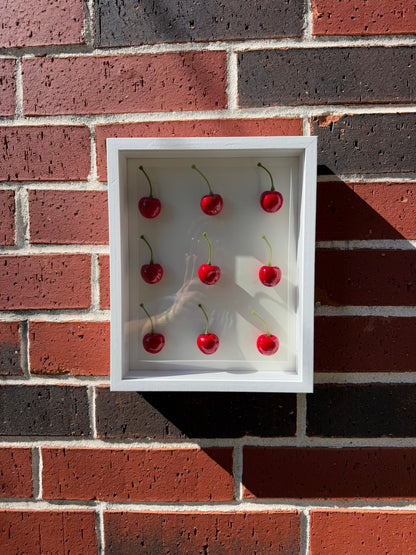Handmade white shadow box with nine glossy red cherries