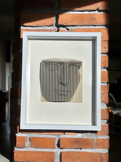 Handmade parametric shadow box of a face formed from fine vertical slats